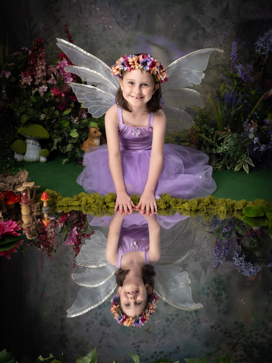 A smiling fairy in purple beside a woodland pool